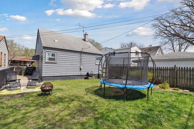 view of yard featuring fence, a trampoline, and a fire pit