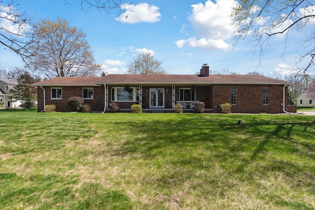rear view of house featuring a yard, brick siding, and a chimney