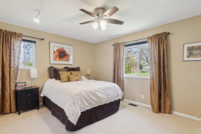 bedroom featuring baseboards, ceiling fan, light carpet, and visible vents