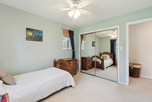 bedroom with a closet, a ceiling fan, baseboards, and light carpet