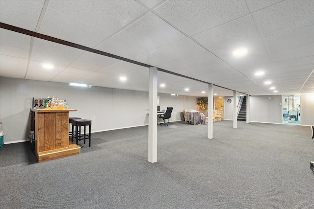 finished basement featuring a dry bar, carpet flooring, stairs, and a paneled ceiling