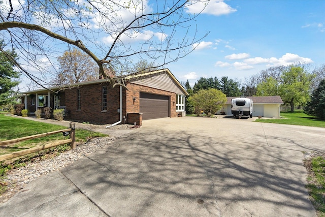 view of property exterior with brick siding, an attached garage, a yard, and driveway