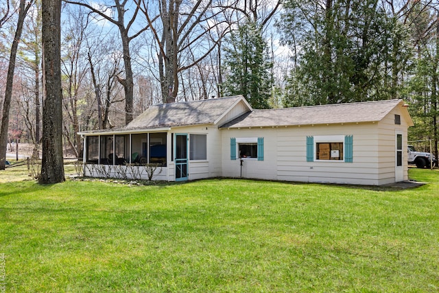rear view of house with a yard, a shingled roof, and a sunroom