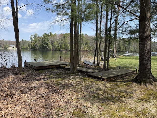 view of dock featuring a yard, a water view, and a forest view