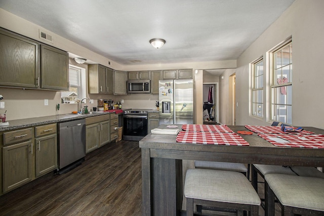 kitchen featuring dark wood-style flooring, visible vents, appliances with stainless steel finishes, dark countertops, and a sink