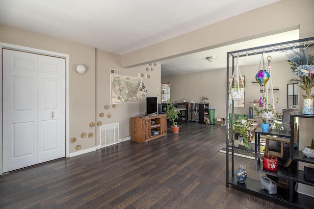 living area featuring baseboards, wood finished floors, and visible vents