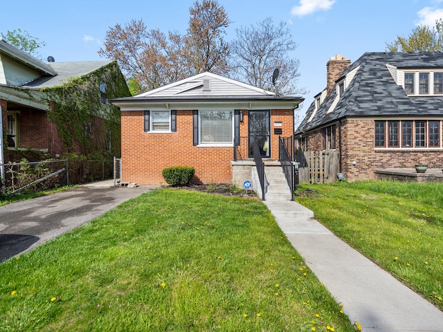 bungalow-style home with a front lawn, brick siding, a chimney, and fence