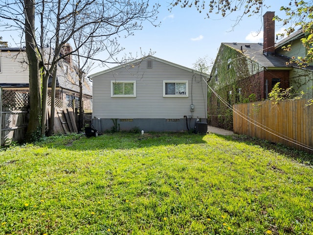 back of house featuring a fenced backyard, central AC, a yard, and crawl space