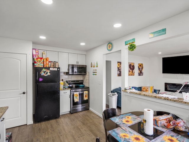 kitchen with light stone counters, white cabinetry, stainless steel appliances, and light wood-style flooring