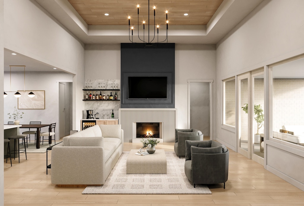 living room featuring a community bar, a raised ceiling, wooden ceiling, light wood-style floors, and a high ceiling