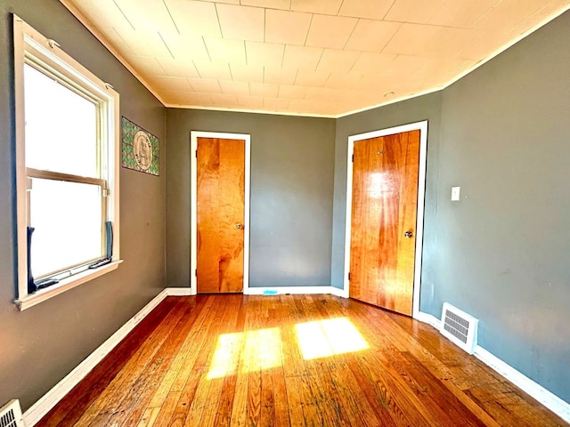 unfurnished bedroom featuring baseboards, visible vents, and wood finished floors