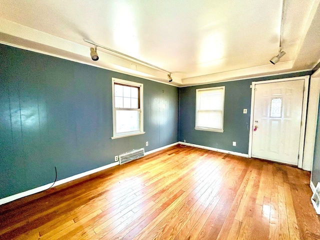 interior space with rail lighting, hardwood / wood-style flooring, baseboards, and visible vents