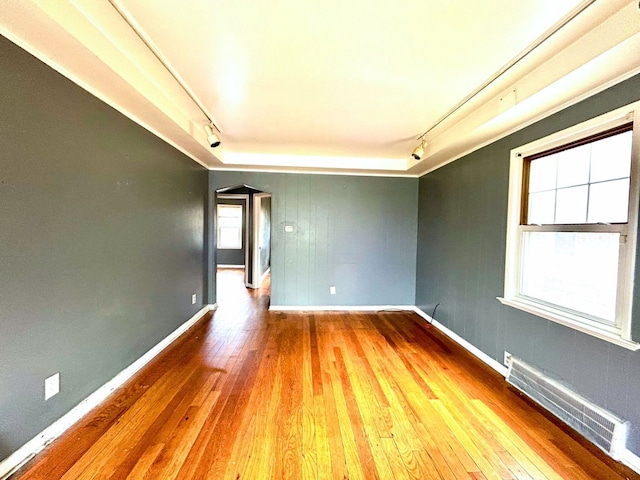 spare room with rail lighting, wood-type flooring, baseboards, and visible vents