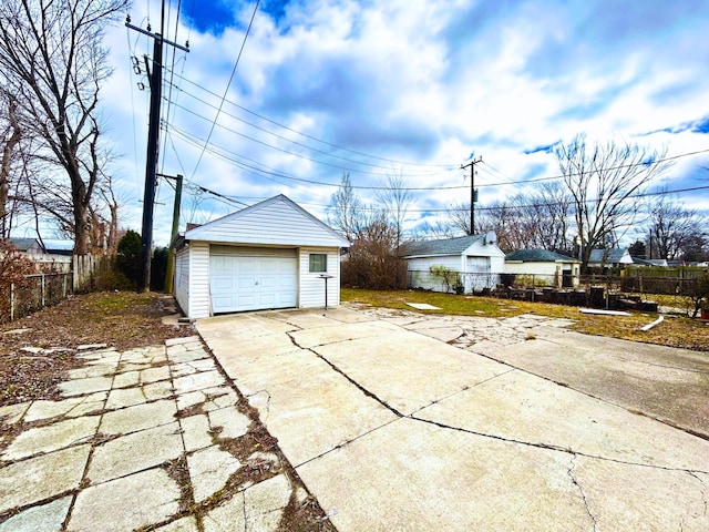 detached garage with concrete driveway and fence