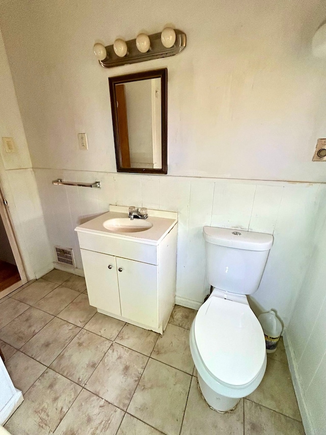 bathroom with toilet, tile walls, visible vents, tile patterned flooring, and vanity