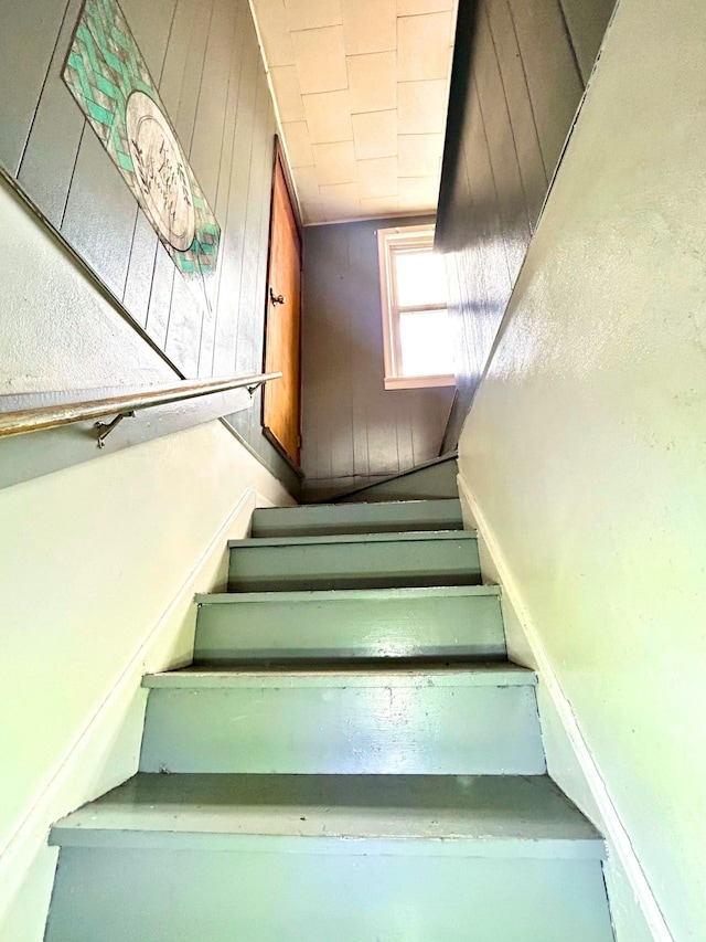stairway featuring wooden walls