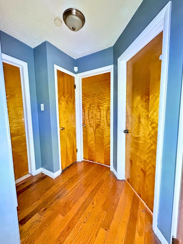 unfurnished bedroom with a closet, a textured ceiling, baseboards, and hardwood / wood-style floors