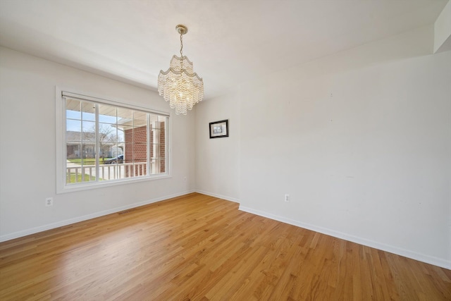 61 Old Carriage Ln, Lapeer, MI 48446 - unfurnished room with light wood-style floors, baseboards, and a chandelier