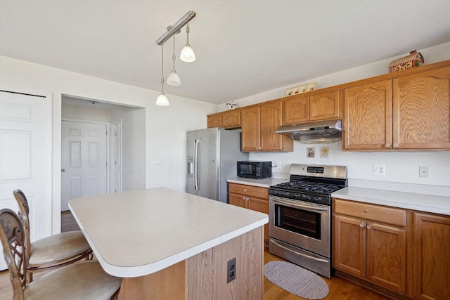 61 Old Carriage Ln, Lapeer, MI 48446 - kitchen featuring appliances with stainless steel finishes, light countertops, decorative light fixtures, a kitchen bar, and under cabinet range hood