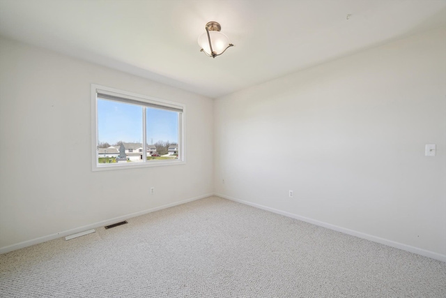 61 Old Carriage Ln, Lapeer, MI 48446 - spare room with light colored carpet, baseboards, and visible vents