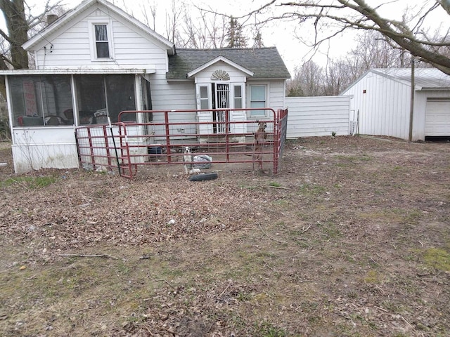 back of house with fence, a shingled roof, and a sunroom