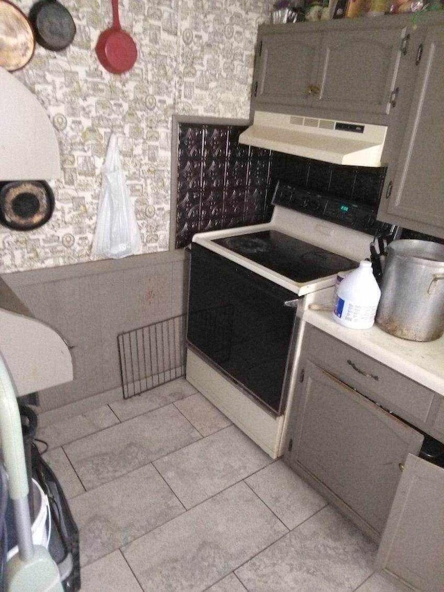 kitchen with exhaust hood, white range with electric cooktop, wainscoting, light countertops, and wallpapered walls