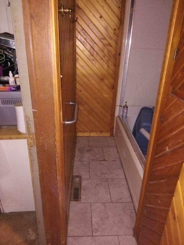 bathroom with wooden walls and tub / shower combination