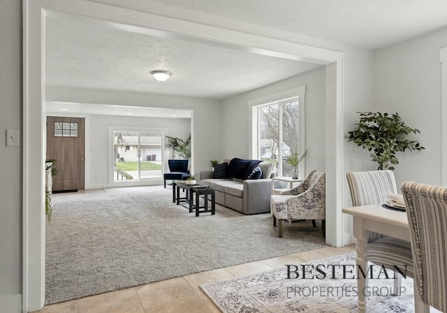 living area with light tile patterned floors, plenty of natural light, and light carpet