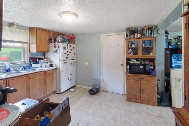 659 N Van Dyke Rd, Imlay City, MI 48444 - kitchen featuring a sink, freestanding refrigerator, black microwave, brown cabinets, and a textured ceiling