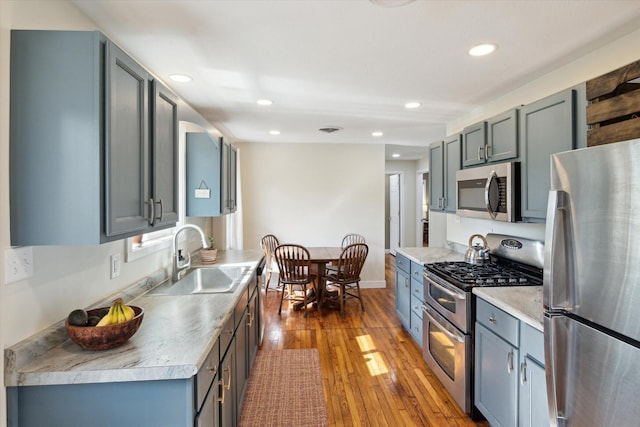 kitchen featuring a sink, light countertops, hardwood / wood-style floors, stainless steel appliances, and recessed lighting