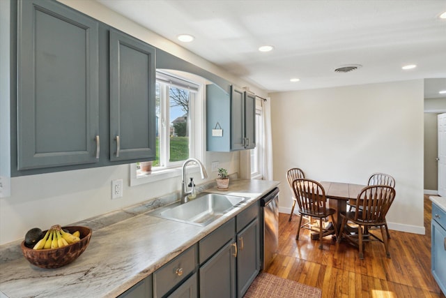 kitchen featuring visible vents, stainless steel dishwasher, dark wood-style floors, light countertops, and a sink
