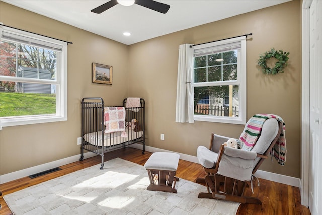 bedroom featuring visible vents, baseboards, wood finished floors, and multiple windows