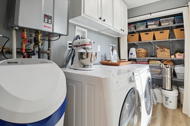 washroom with tankless water heater, light wood-style flooring, cabinet space, and washing machine and clothes dryer
