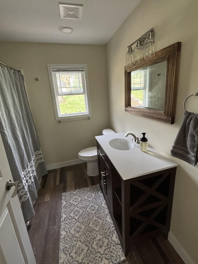 full bath featuring visible vents, vanity, wood finished floors, toilet, and baseboards