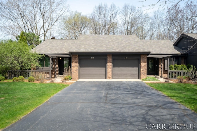 view of front of house with an attached garage, aphalt driveway, covered porch, and a front yard