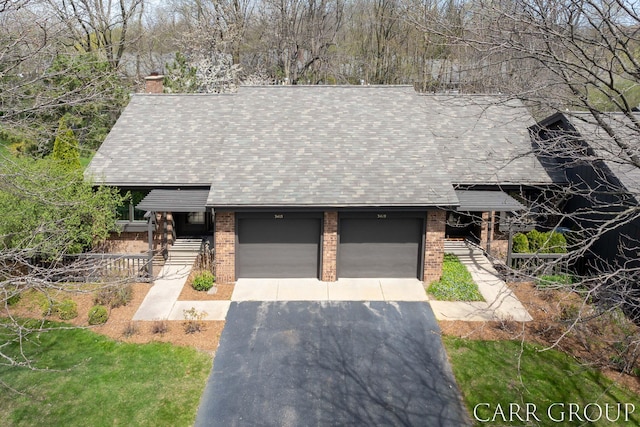 view of front of property with driveway, a chimney, a garage, brick siding, and a shingled roof