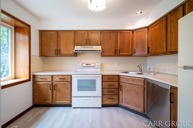 kitchen featuring brown cabinets, a sink, white appliances, light countertops, and extractor fan