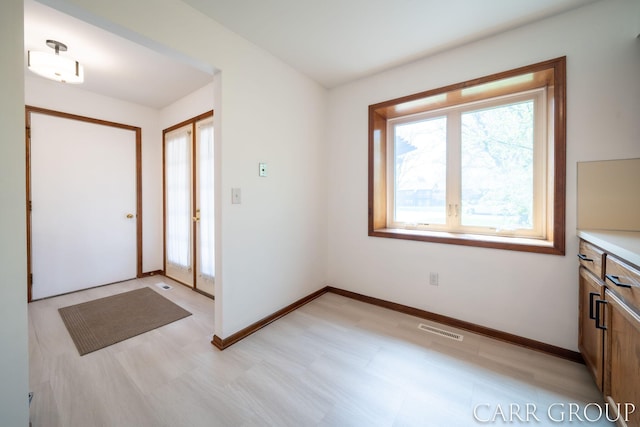 foyer entrance with baseboards and visible vents