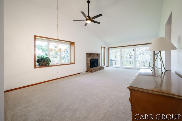 unfurnished living room with a brick fireplace, high vaulted ceiling, baseboards, ceiling fan with notable chandelier, and carpet