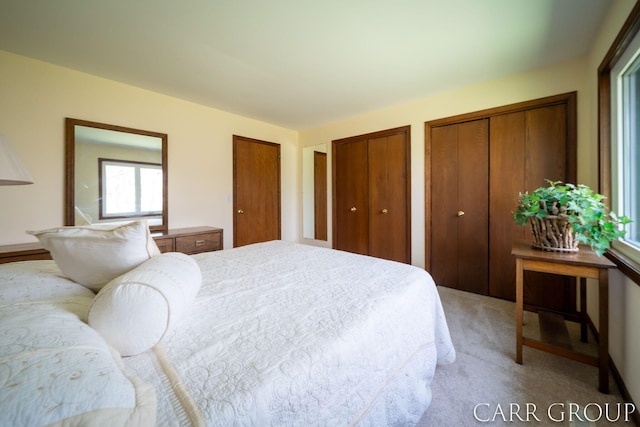 bedroom with light colored carpet and multiple closets
