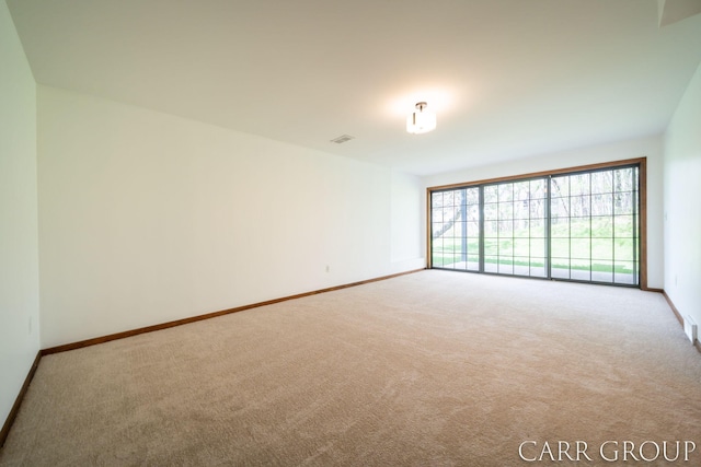 carpeted spare room featuring baseboards and visible vents