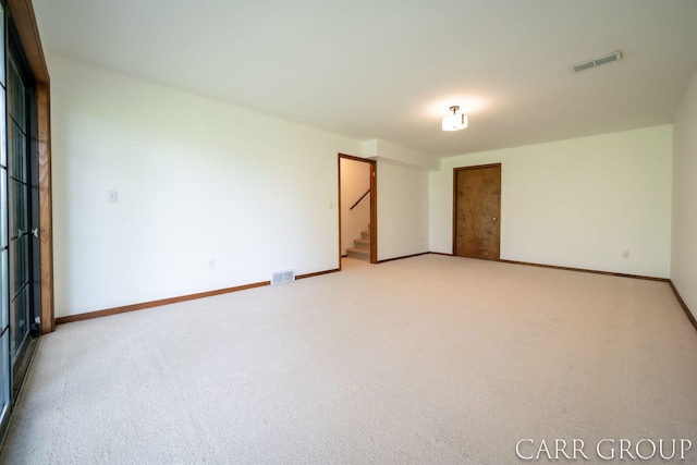 unfurnished room featuring visible vents, baseboards, light carpet, and stairway