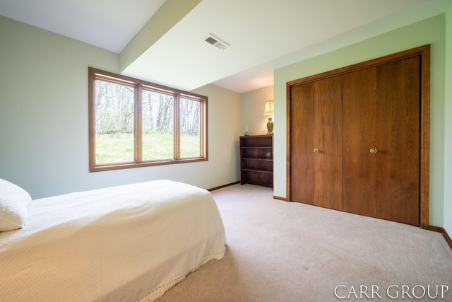 carpeted bedroom with visible vents, baseboards, and a closet
