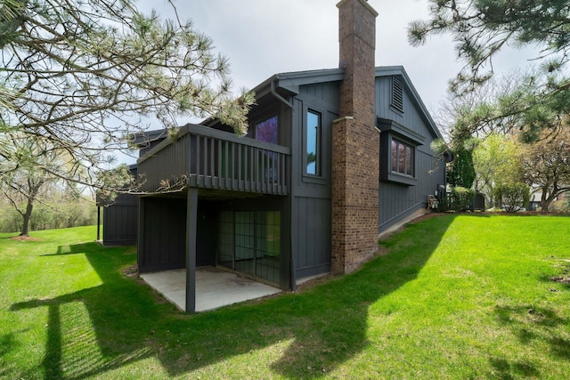 rear view of property with a lawn, a wooden deck, a chimney, and a patio area