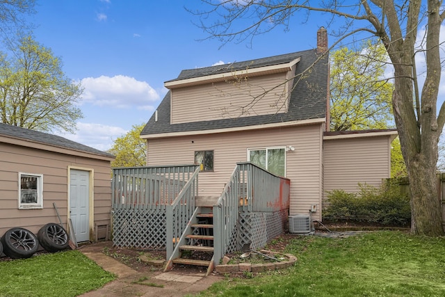 rear view of house featuring roof with shingles, a wooden deck, central AC unit, a chimney, and a yard