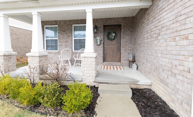 view of exterior entry with covered porch and brick siding