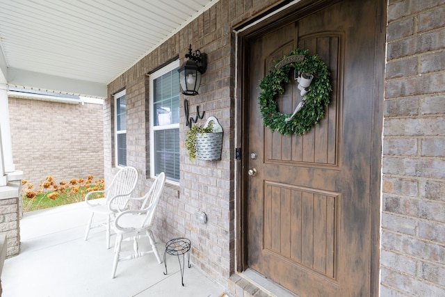 property entrance featuring a porch and brick siding
