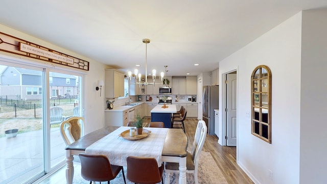 dining area featuring recessed lighting, baseboards, a notable chandelier, and light wood-style floors