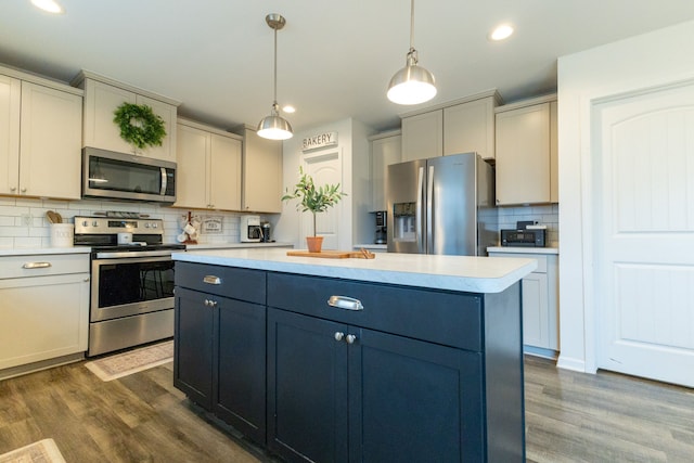 kitchen featuring decorative backsplash, pendant lighting, dark wood-type flooring, light countertops, and appliances with stainless steel finishes