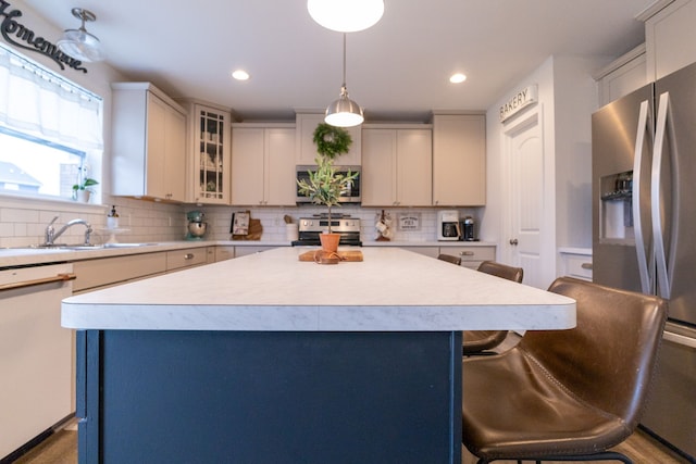 kitchen featuring a breakfast bar, a sink, light countertops, stainless steel appliances, and tasteful backsplash